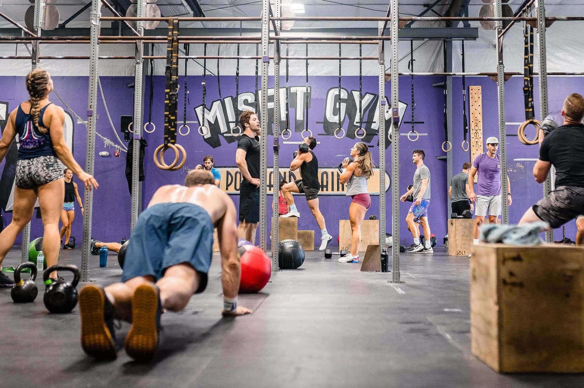 A full class working across the main floor under the Misfit mural, one member mid push-up up front