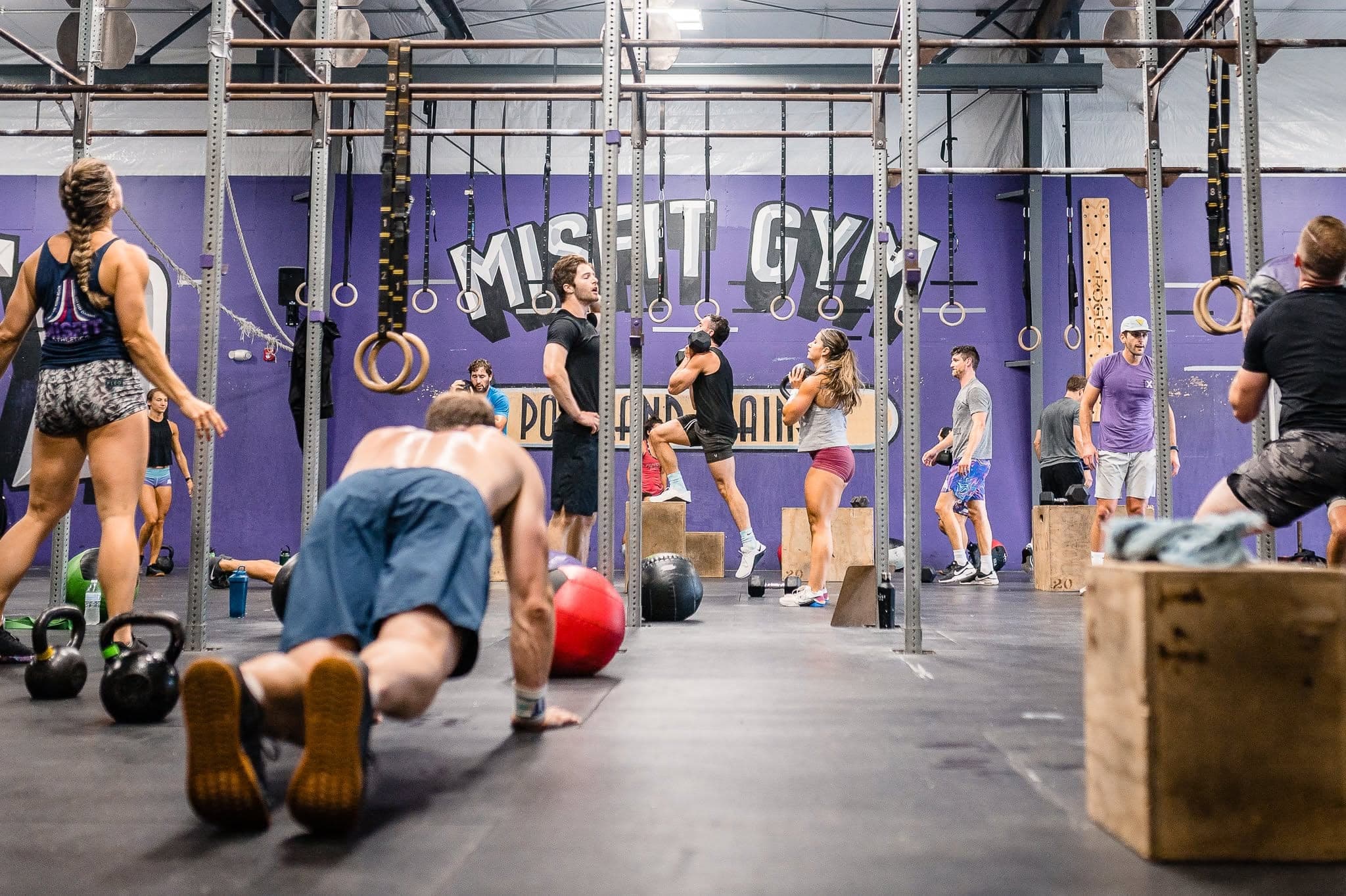 A full class working across the main floor under the Misfit mural, one member mid push-up up front