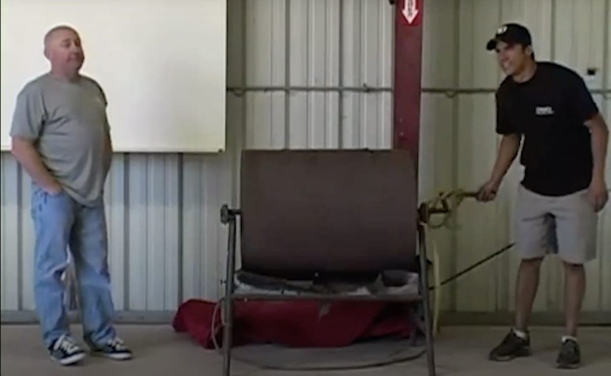 Two men beside the rotating steel drum hopper in a metal barn at the CrossFit ranch